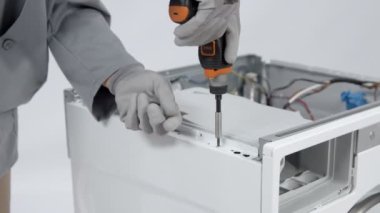 Çamaşır makinesinin yan tarafındaki küçük elektrikli matkapla vidayı sökmek.