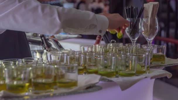 调酒师把柠檬和酸橙汁巧妙地倒入装有不同寻常的酒类饮料和柠檬片的杯子中 — 图库视频影像