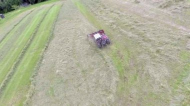 Hava görüntüsü. Tarım makineleri samanların etrafında dönüyor. Birisi sarp bir tepede saman hazırlıyor..