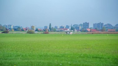 Bir uçak piste indikten sonra yavaşça duruyor. Güneşli bir gün ve arka planda bir kasaba görülebilir.