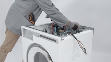 Çamaşır makinesinin önünü ve arkasını mavi kabloyla bağlayan tamirci..