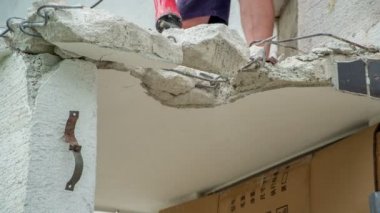 Erkek işçi güçlü bir kaya matkabı kullanarak beton ve çelik yapımını yok ediyor..