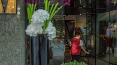 Girişteki güzel çiçek aranjmanı ve kırmızı-beyaz üniformalı temizlikçi kadın vakumu yeni bitirdi..