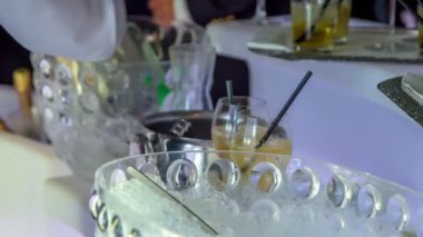 Barmen soğuk bir şişe tatlı içkiyi alır ve biraz da özel alkol dolu bardaklara döker..