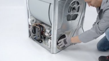 Bir adam çamaşır makinesinin drenaj pompası filtresini çıkarıyor ve tamir edecek..