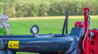 Çim kesme makinelerinin üstünde bir barometre var. Arka planda güzel bir yeşil çim alanı var..