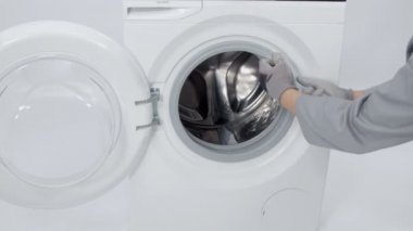 Bir adam çamaşır makinesi nin kauçuğundan çıkıyor. Çamaşır makinesini tamir edecek..