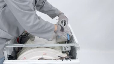 Bir tamirci çamaşır makinesini tamir ederken tornavida kullanıyor..