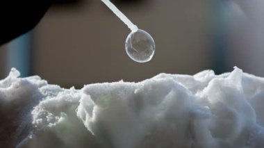 Bir adam yavaş yavaş büyük bir kabarcık yapmak için bir saman içine üfleme olduğunu. Kabarcık th yüzeyinde kalır.