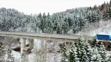 Araçlar viyadük üzerinde bir otoyol üzerinde sürüş vardır. Kış mevsimi ve doğa karla kaplı. Havadan çekim.
