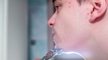 Genç bir adam sakalını tıraş ediyor ve aynada kendine bakıyor..