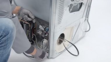 Bir tamirci çamaşır makinesinden şeritler çıkarıyor. Cihazı tamir ediyor..