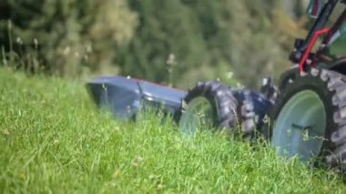 Güzel bir yaz günü. Bir çiftçi traktörü oturuyor ve o yokuş yukarı sürüş ve bir çim kesme makineleri ile çim kesiyor.