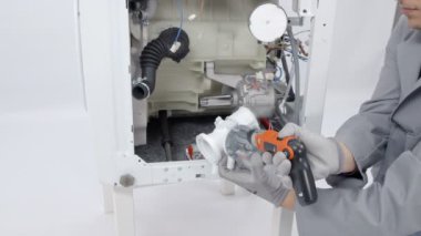 Bir adam çamaşır makinesinin tüm parçalarını kontrol ediyor ve bir sorun bulmak ve düzeltmek için çalışıyor.