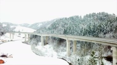 Araçlar kış aylarında bir viyadük üzerinde bir karayolu üzerinde sürüş vardır. Manzara karla kaplı. Havadan çekim.