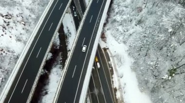 Bir köy yolu köprünün altından geçiyor. Her iki yolda da araba kullandığını görebiliyoruz. Kış zamanı..