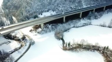 Bir ülke yolu üzerinde bir otoyol olan bir köprü altında çalışır. Havadan ateş. Kış zamanı ve manzara beyaz..