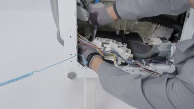 Bir adam çok çalışıyor ve çamaşır makinesindeki bir sorunu çözmeye çalışıyor..