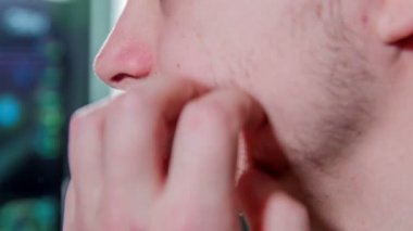 Genç bir adam sakalını kontrol ediyor ve tıraş etme zamanının geldiğini düşünüyor..