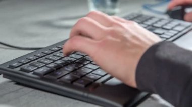 Genç bir adam masada oturuyor ve o siyah klavye bir şey yazıyor.