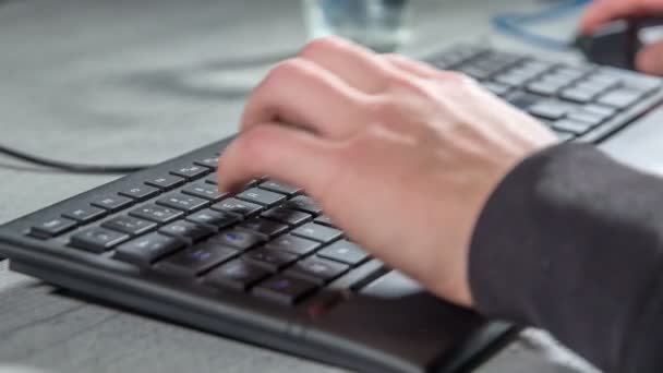 一个年轻人正坐在桌旁 他正在黑色键盘上打字 — 图库视频影像
