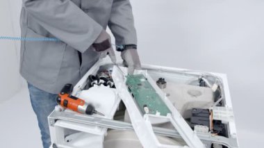 Bir tamirci tamamen çamaşır makinesi üzerinde bir kontrol paneli sökümü. Tam aygıt düzeltmeye ihtiyacı.