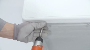 Bir adam matkapla vidayı gevşetiyor..