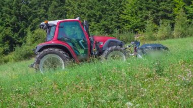 Kırmızı bir traktör tepenin ortasında hareketsiz duruyor. Yaz mevsiminde..