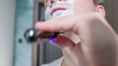 Genç bir adam sakalının yarısını traş etti bile. Yüzünde hala bir sürü köpük var..