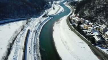 Bir tren yavaş yavaş şehirden ayrılıyor ve bir sonraki istasyona doğru ilerliyor. Doğa güzel ve beyaz. Kış zamanı. Havadan çekim.