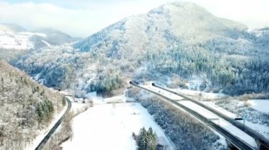 Kış mevsiminde güzel doğa. Bir otoyol var ve araçlar üzerinde sürüyor. Ormanlar kar yüzünden beyaz.