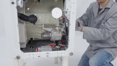 Çamaşır makinesi tamir ediliyor. Bir tamirci sorunu çözmek için çok çalışıyor..