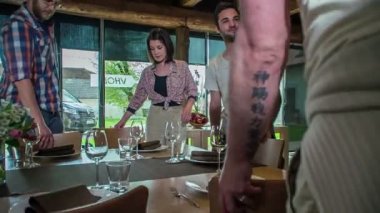 Arkadaşlar Littoral Bölgesi 'ndeki bir restoranda bir masaya oturmak için sandalye taşıyorlar..