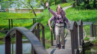 İki arkadaş onları karşılamak için köprüden geçerken arkadaşlarına el sallıyor. Parkta gerçekten güzel bir gün..