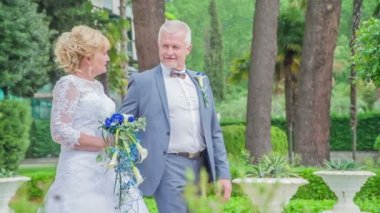 Gelin ve damat parkta yürüyorlar ve fotoğraflardan bahsediyorlar..
