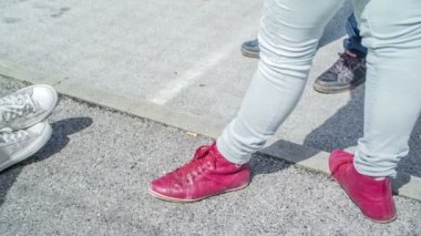 Farklı renkte spor ayakkabıları olan insanlar sokakta dikiliyorlar..