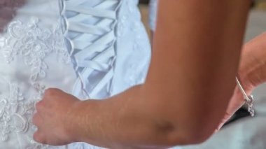 Nedime gelinin gelinliğini bağlamasına yardım ediyor..