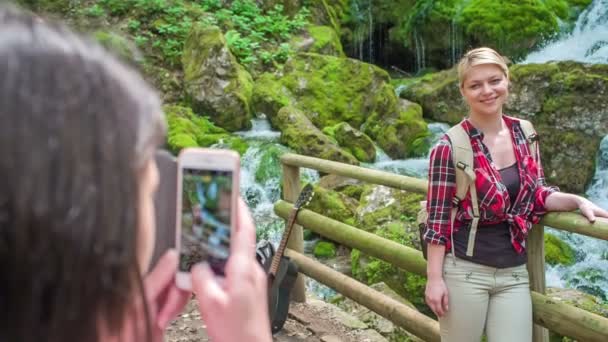 一个女孩正在瀑布边给她的朋友拍照 每年的这个时候 大自然都是美丽的 — 图库视频影像