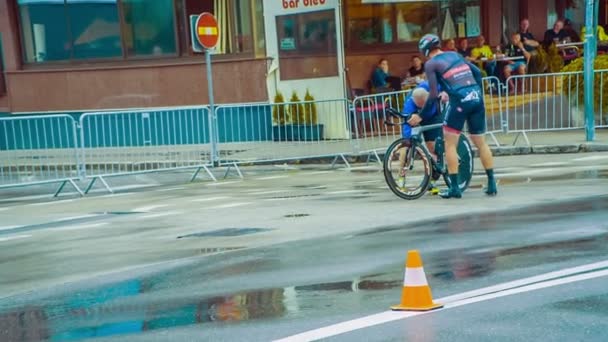 教练帮助这位运动员修理他的自行车有一些问题 由于下雨 道路又湿又滑 — 图库视频影像
