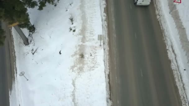 汽车在乡间公路上双向行驶 雪覆盖着周围的森林 空中射击 — 图库视频影像