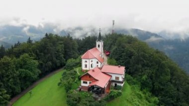 Hom / Zalec, Slovenya - 15. Avgust 2018 Tepenin tepesinde güzel bir kilise bulunur ve çevrede sadece doğa vardır. Hava görüntüsü.