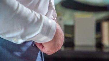 Bir damat pantolonuna kemer takıyor. Düğün töreni için hazırlanıyor..
