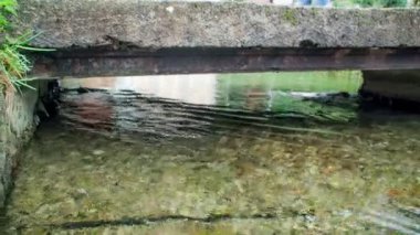 Nehir akıyor ve nehrin karşısındaki köprüde bir adam yürüyor..