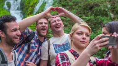 Arkadaşlar şakalar yapıyor ve güzel doğada bir sürü fotoğraf çekiyorlar. Şu anda şelalenin yanında duruyorlar..