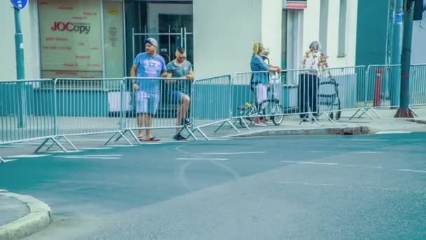 有几个人站在篱笆后面等着公路上的自行车赛手经过 — 图库视频影像