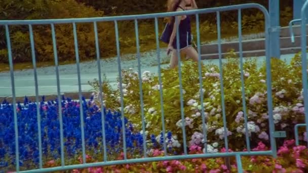 Ένα Νεαρό Κορίτσι Περπατάει Στο Πεζοδρόμιο Υπάρχουν Πολλά Λουλούδια Εκεί — Αρχείο Βίντεο