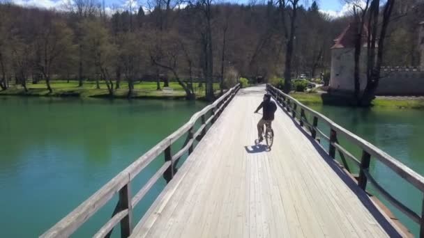 在城堡附近的桥上骑自行车的年轻人的镜头 — 图库视频影像