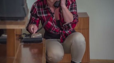 Genç bir kadın eğleniyor ve eski moda bir telefondan birini arıyormuş gibi yapıyor..