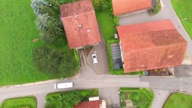 Caddede beyaz bir minibüs sürüyor. Gerçekten güzel ve yeşil bir semt. Yaz geldi ve her şey çiçek açıyor..