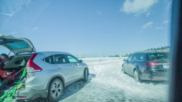 雪の多い駐車場には車やバスが停まっています 人々はスキーの準備をしている — ストック動画